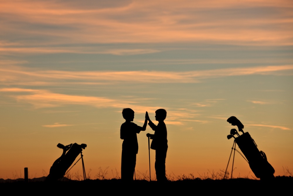 silhouette of young junior golfers